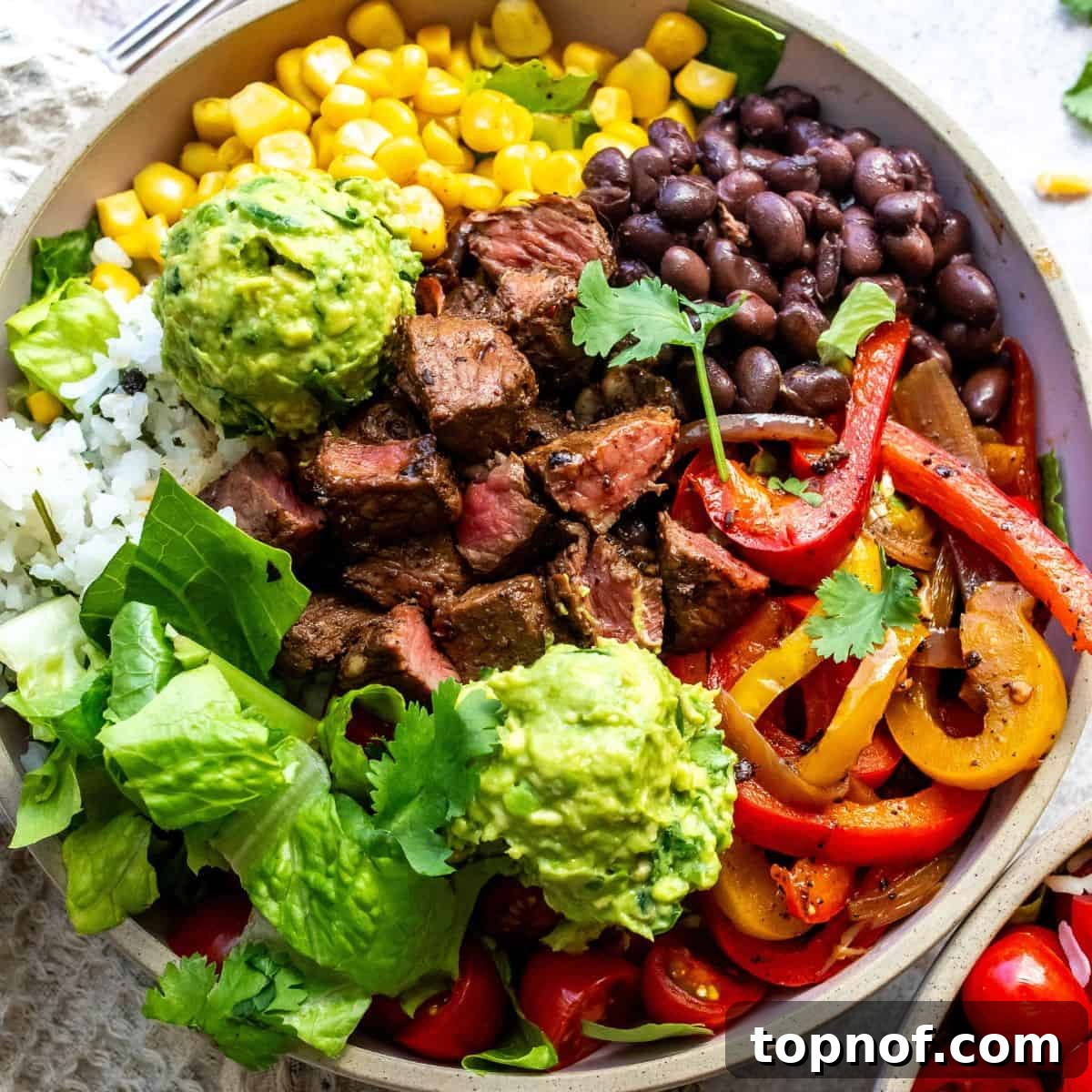 A ceramic bowl filled with tender steak and rice, garnished with numerous fresh toppings and a fork.