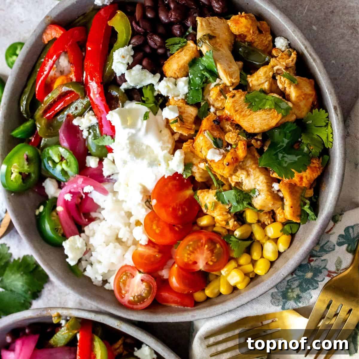 Grey ceramic bowls filled with cilantro lime chicken and abundant vegetable toppings.