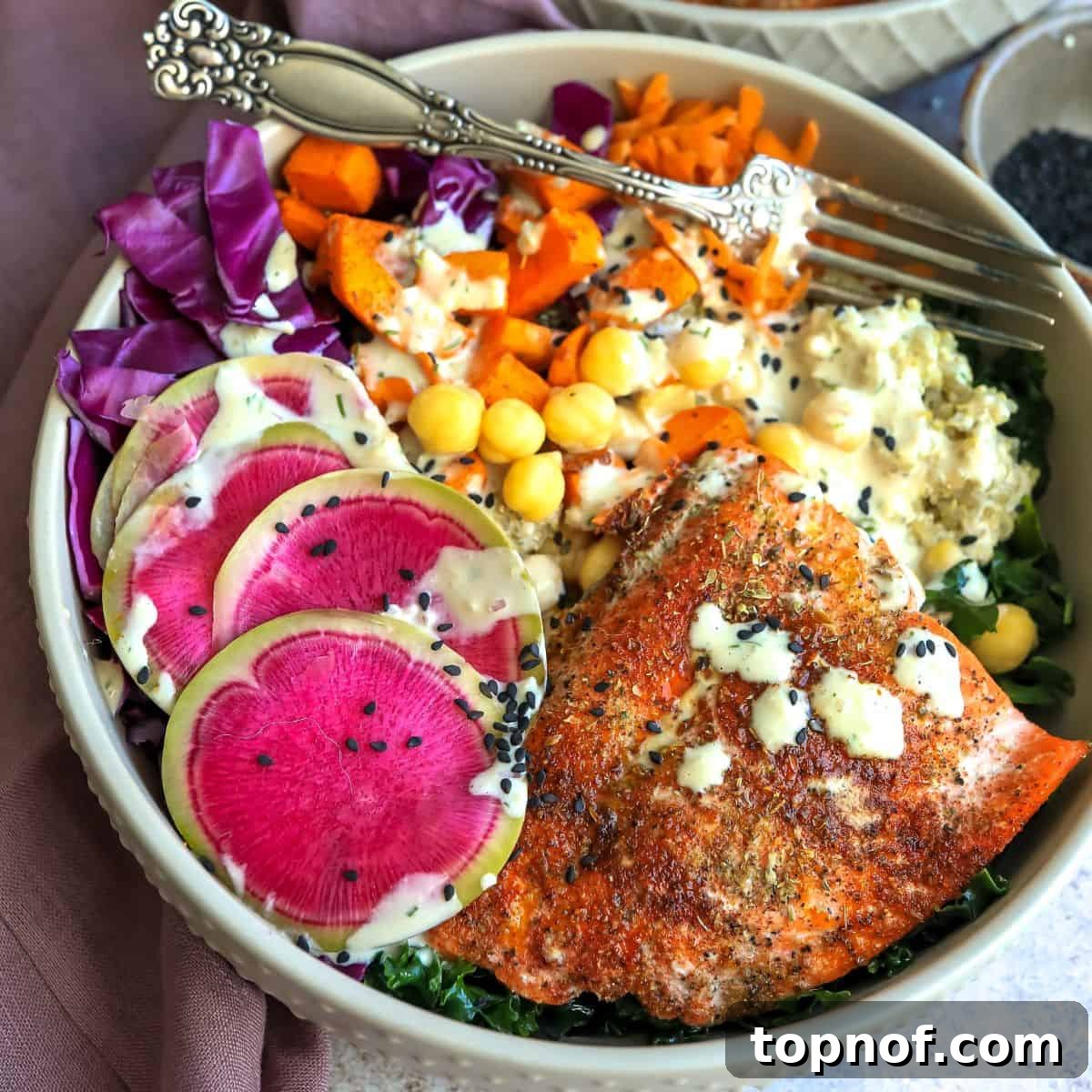 Close-up of a colorful bowl featuring bright vegetables and salmon on top, with a fork ready to enjoy.