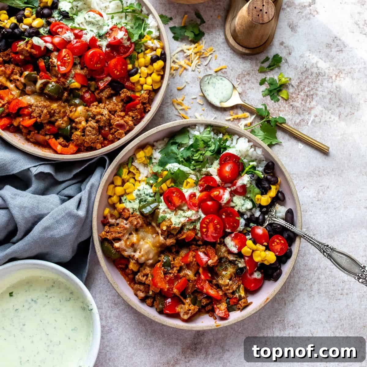 Pink bowls filled with seasoned ground beef and various toppings, with sauce and cheese on the side.