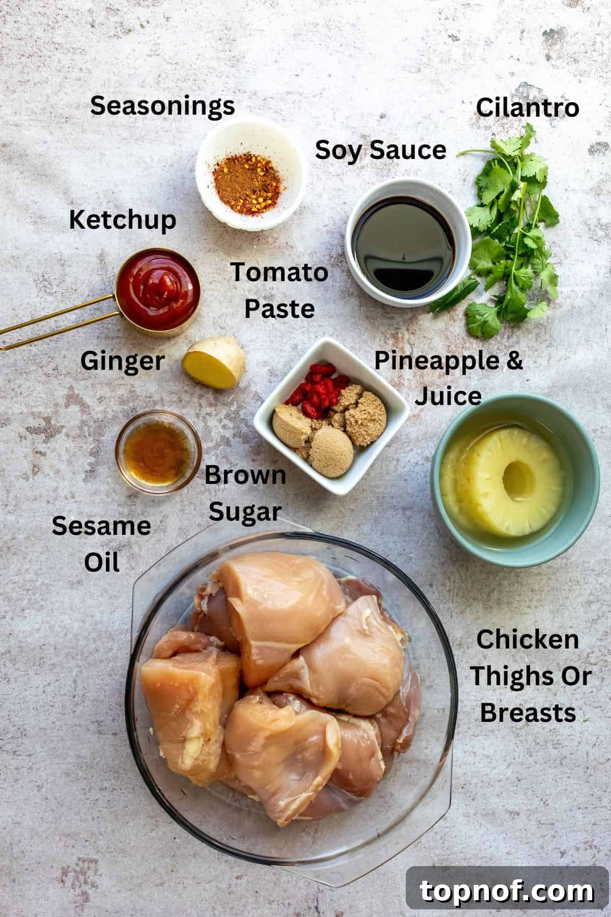 Aloha BBQ Chicken 3 A collection of fresh ingredients for Hawaiian BBQ Chicken arranged in small bowls and measuring cups on a kitchen counter, including pineapple, soy sauce, ginger, garlic, and spices.