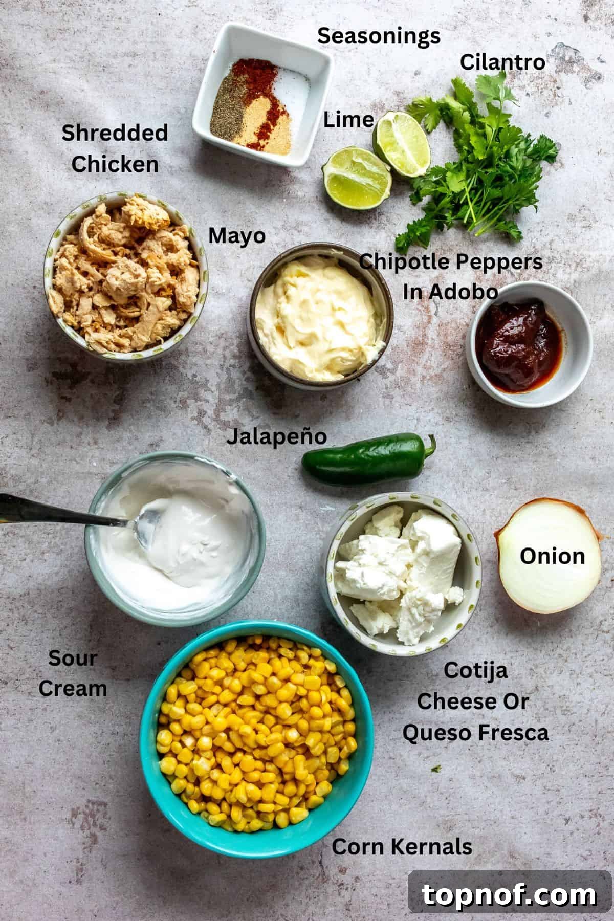 Creamy Elote Bake 3 An overhead view of various fresh ingredients neatly arranged in separate containers with labels, including vibrant corn kernels, finely diced onions, spicy jalapeños, creamy mayonnaise, tangy sour cream, crumbly cotija cheese, fresh cilantro, and a blend of aromatic spices, all ready for the Mexican street corn casserole preparation.