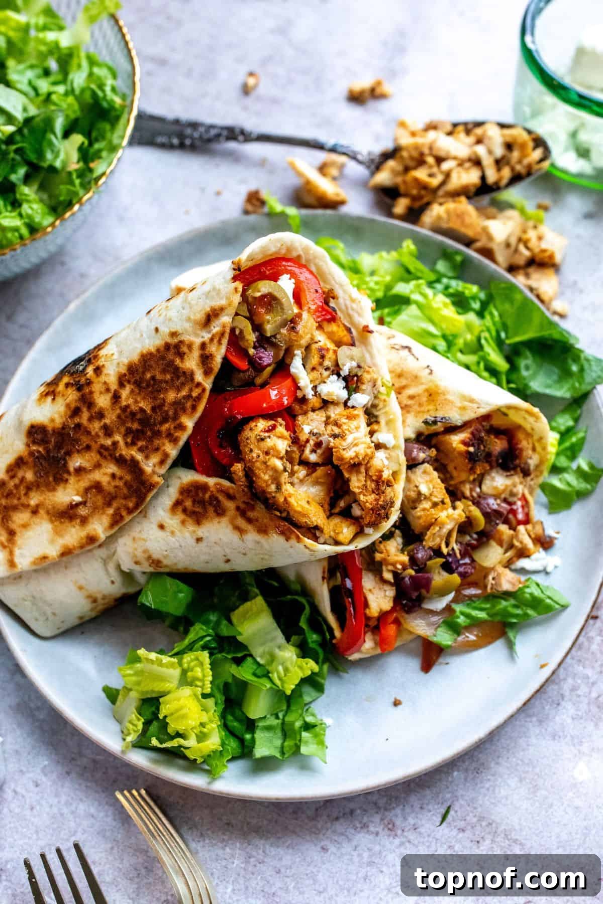 Vibrant Mediterranean Wraps 2 Mediterranean chicken wraps arranged beautifully on a plate, surrounded by fresh lettuce leaves, ready to be enjoyed.