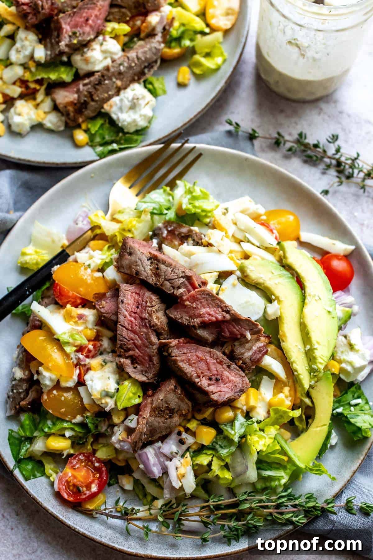 Hearty Steak Salad 5 A beautifully presented steak house salad on a white plate, garnished with fresh herbs, ready to be enjoyed.