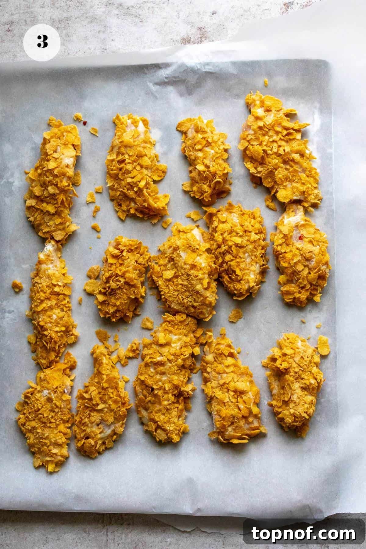 Chicken battered in ingredients on a baking sheet.