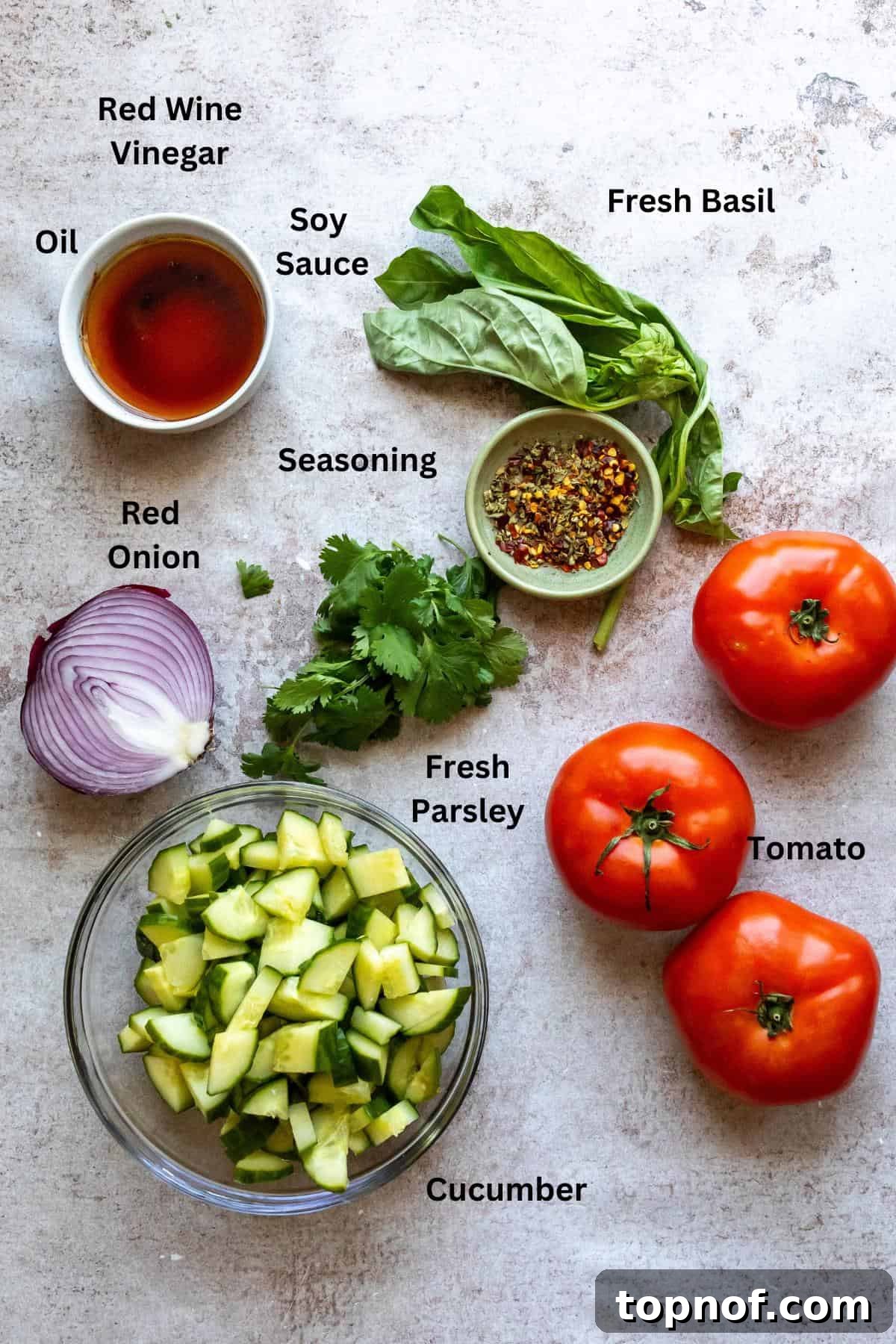 Garden Fresh Tomato Cucumber Salad 3 Fresh ingredients laid out on a kitchen counter, including cucumbers, tomatoes, red onion, and fresh herbs, ready for salad preparation.