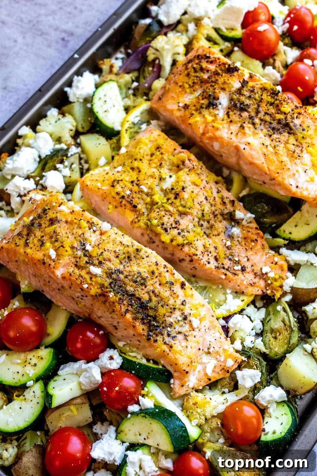 Zesty Sheet Pan Salmon and Roasted Garden Vegetables 2 A beautifully plated lemon pepper salmon fillet served over a bed of roasted sheet pan vegetables, garnished with fresh herbs and lemon wedges.