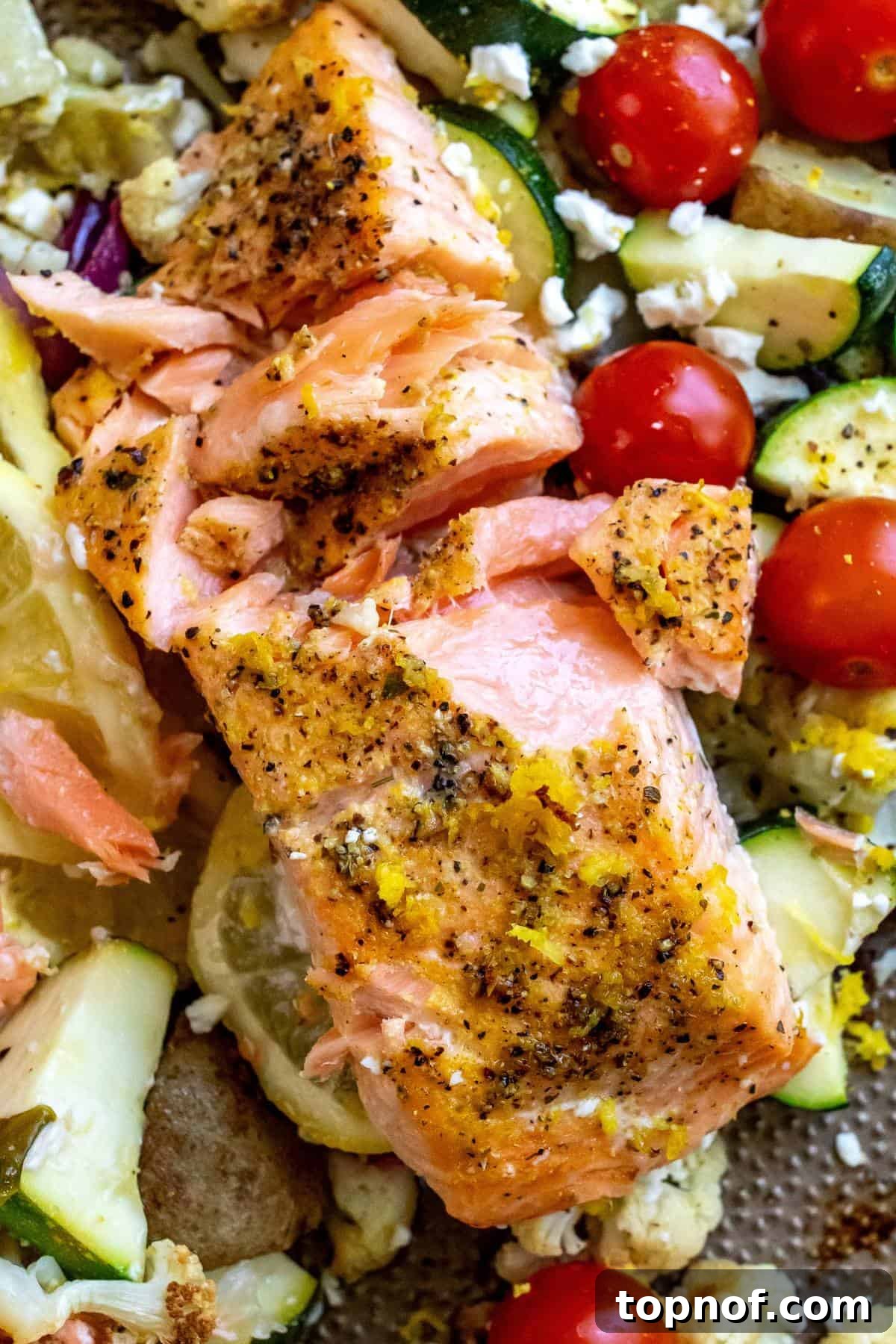 Zesty Sheet Pan Salmon and Roasted Garden Vegetables 5 A close-up shot of a perfectly cooked lemon pepper salmon fillet, flaky and golden, with roasted vegetables blurred in the background.