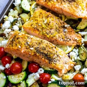 An image of lemon pepper salmon served over baked veggies.