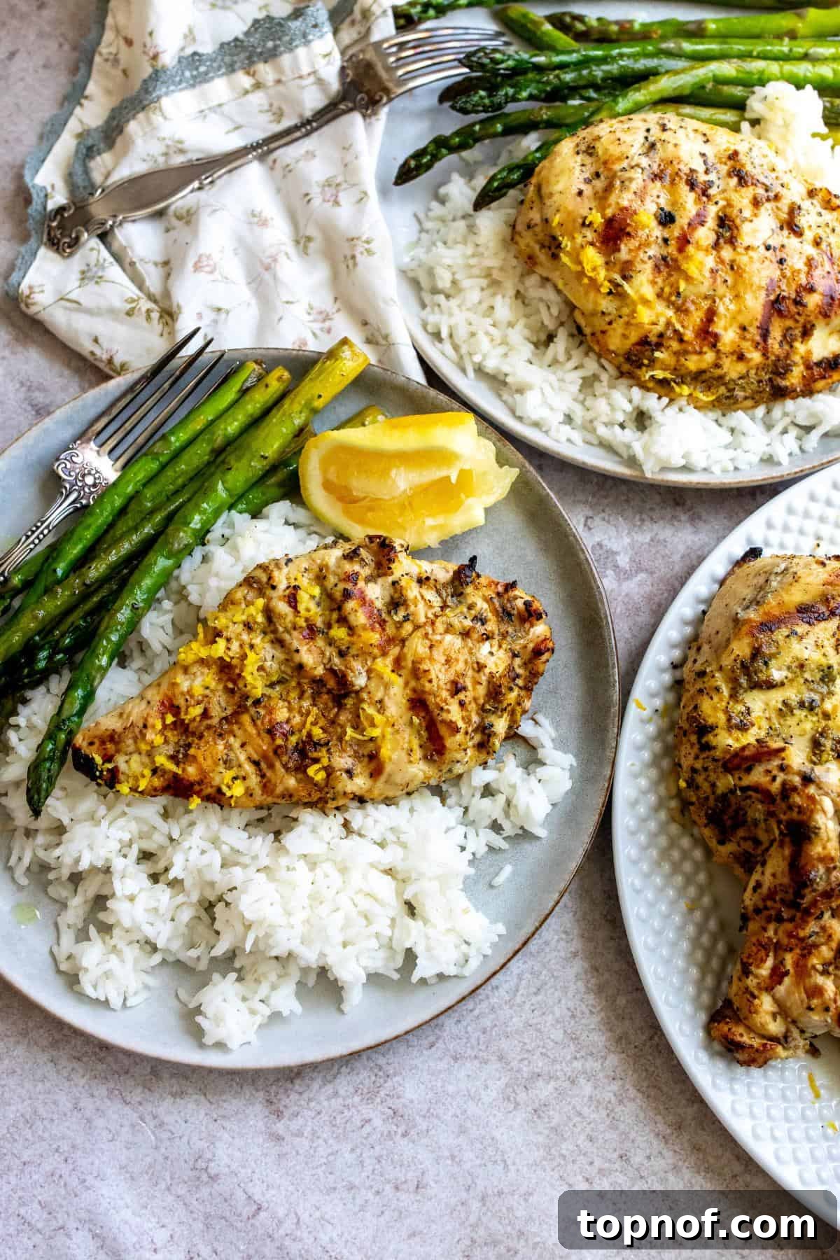 Peppery Citrus Chicken 2 Grey plates with lemon pepper chicken on rice, garnished with fresh lemon wedges.