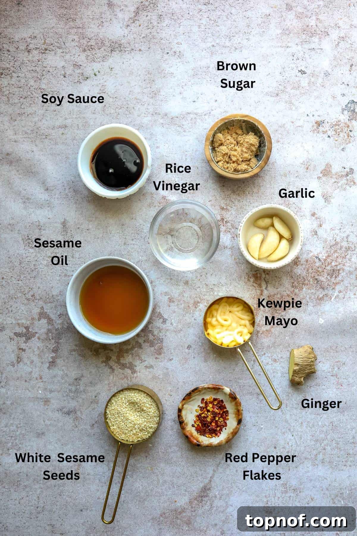 Savory Toasted Sesame Drizzle 3 An array of small bowls and measuring cups showcasing the fresh ingredients required for the roasted sesame dressing, including ginger, garlic, and sesame seeds.