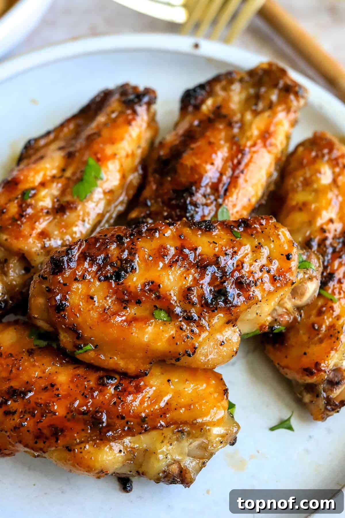 Sticky Sweet Heat Wings 5 White ceramic plate with sauce hot honey wings in it. Up close photo.