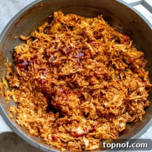 A close up image of shredded BBQ chicken in a skillet, ready to be served.