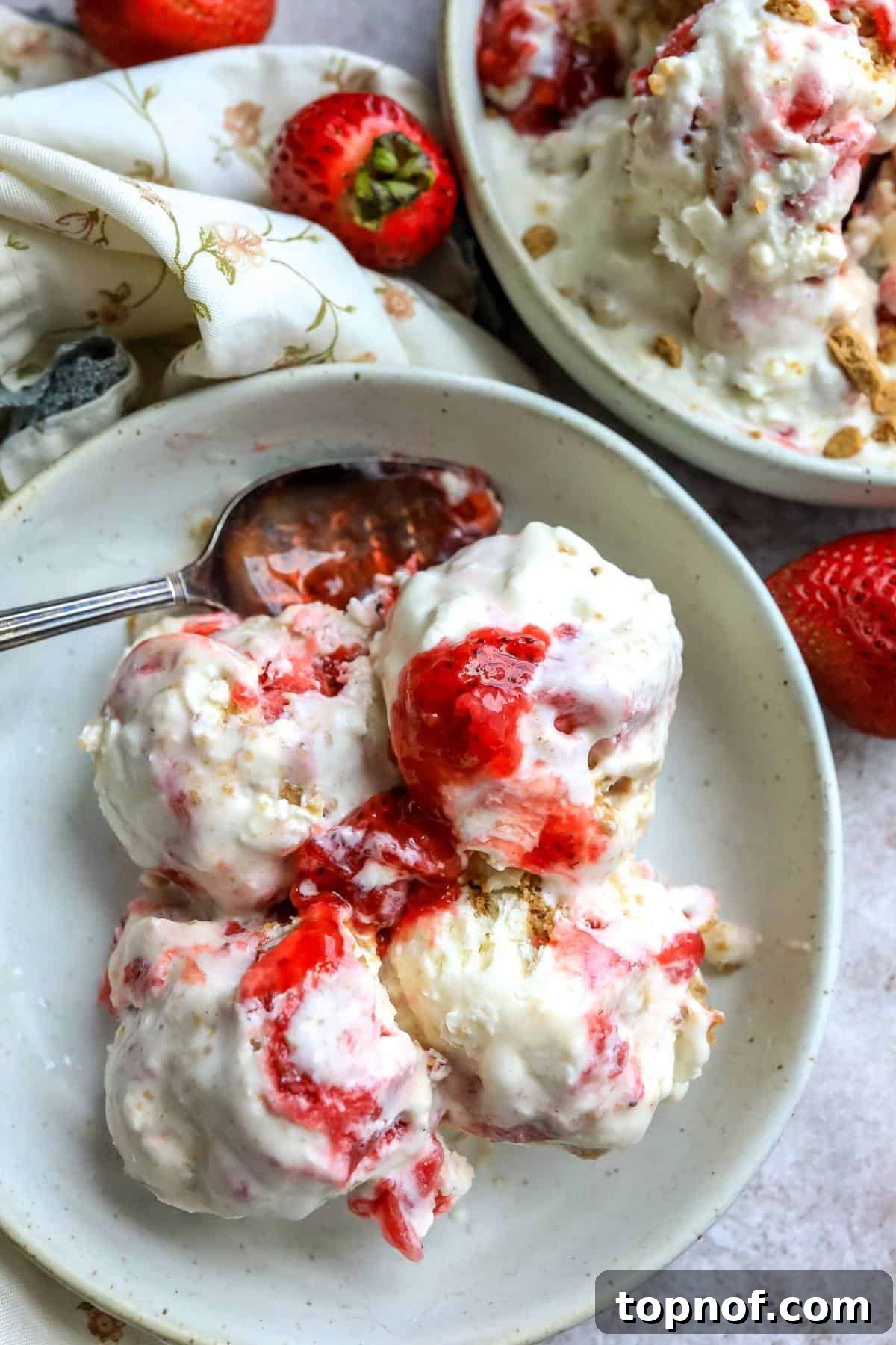 Homemade No-Churn Strawberry Cheesecake Indulgence 2 An overhead image of four scoops of strawberry cheesecake ice cream in a bowl, garnished with fresh strawberries.