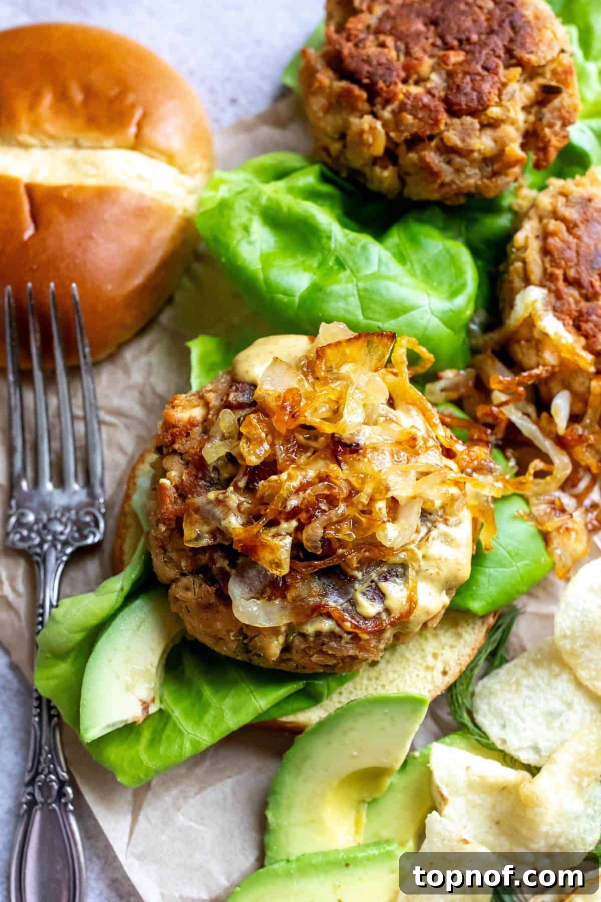 Up close photo of canned salmon burger with onions on top. A silver fork to the side.