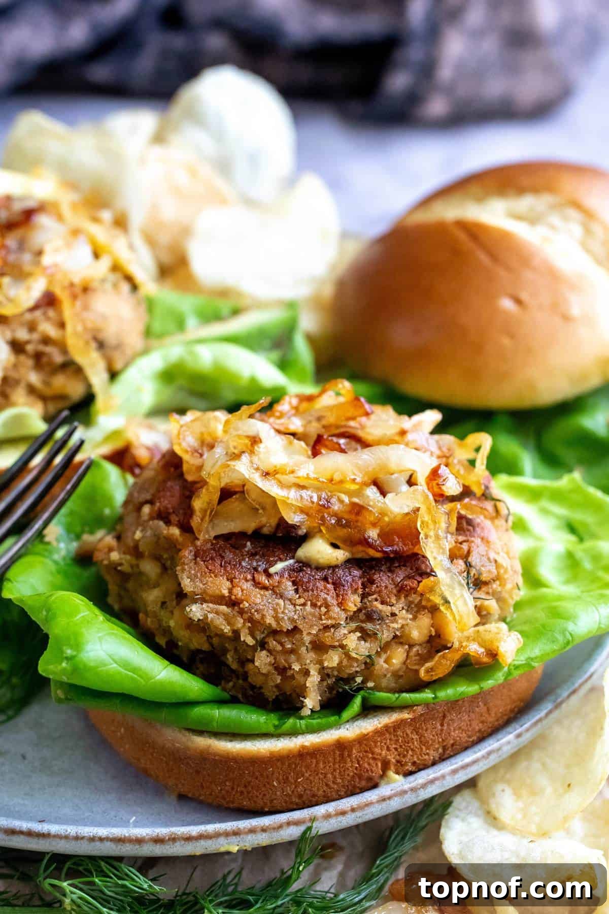 Up close photo of canned salmon burgers on a bun with a fork. 