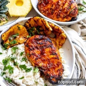 White pottery bowl with glazed Chicken Pineapple Adobo served over rice. Overhead shot.