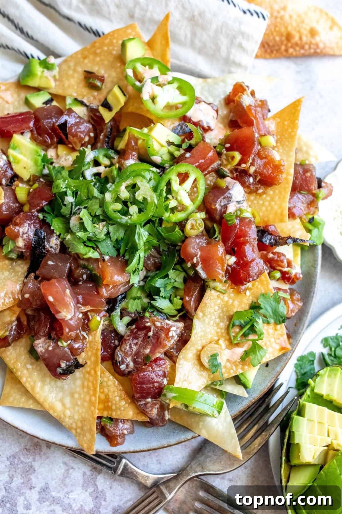 Freshly prepared Tuna Poke Nachos on a platter, garnished with various toppings.