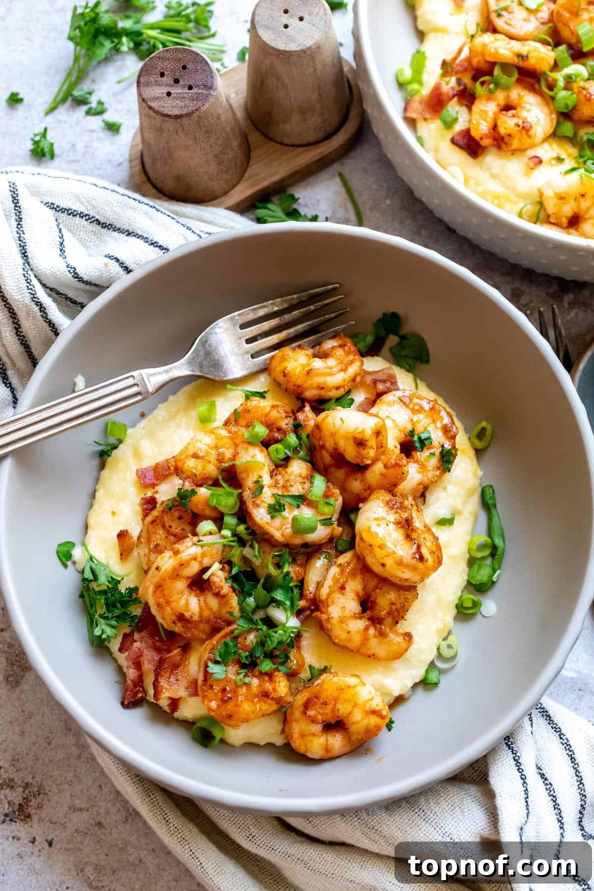 A beautifully presented bowl of New Orleans Shrimp and Grits, garnished with fresh herbs and crispy bacon, ready to be enjoyed.