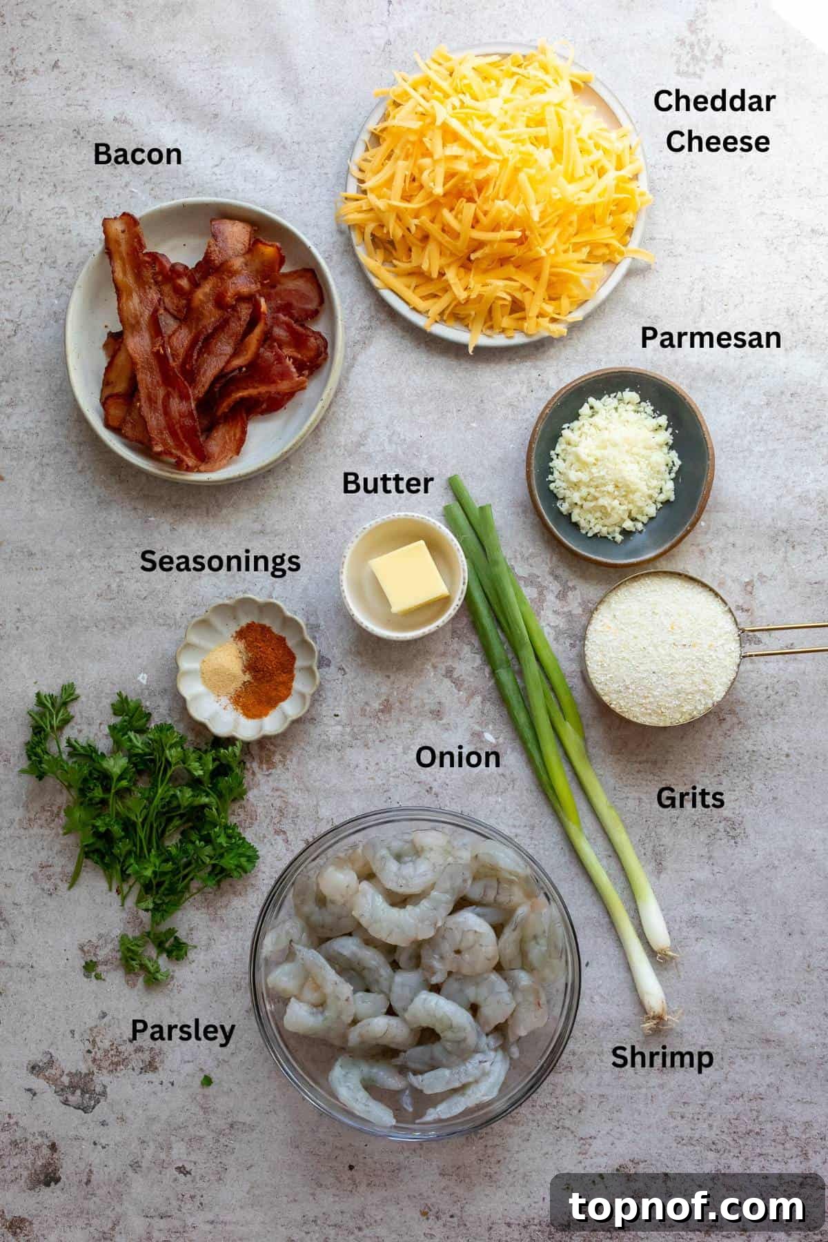 Various fresh ingredients for New Orleans Shrimp and Grits, including raw shrimp, cheese, butter, and spices, meticulously arranged in bowls and cups.