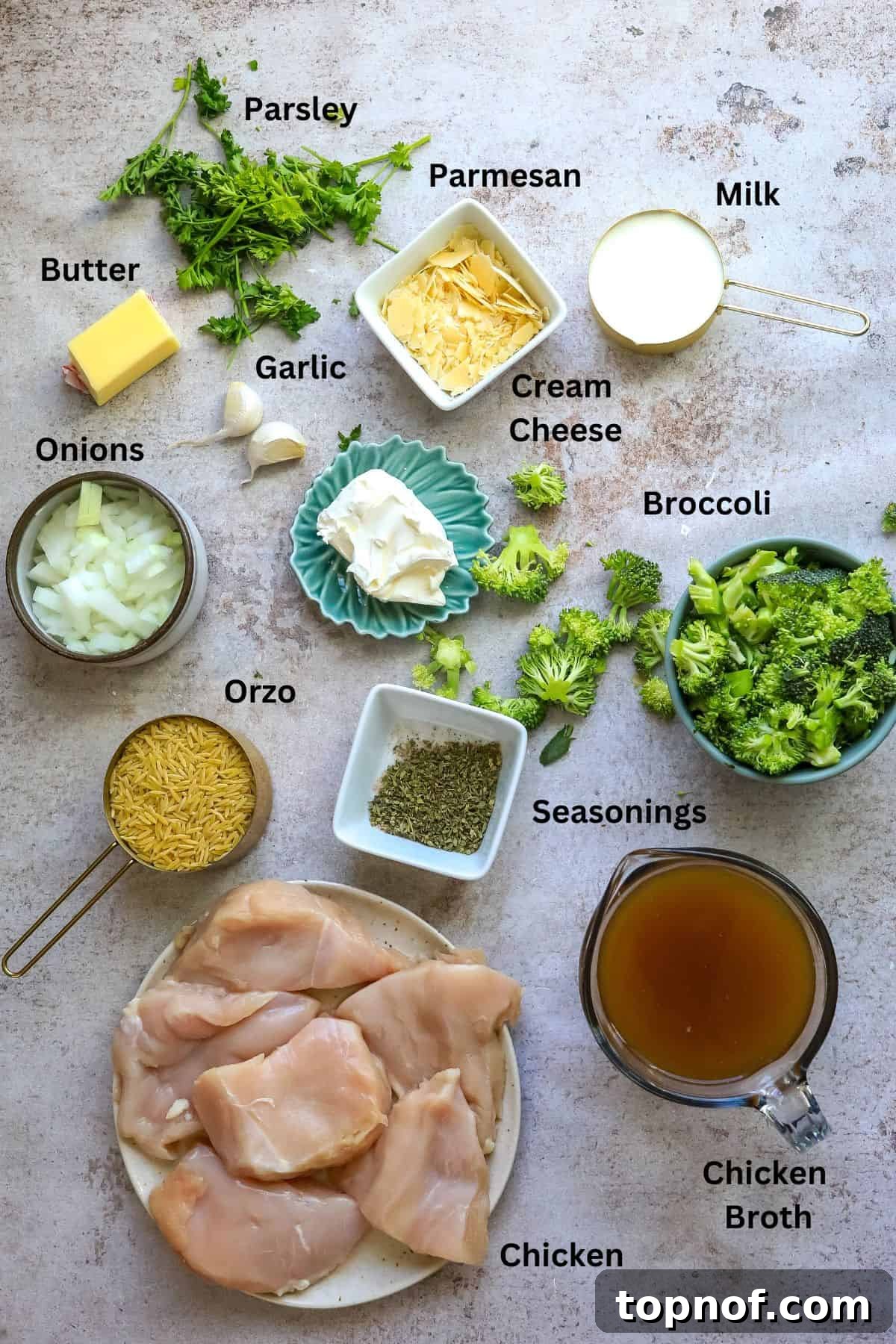 A collection of fresh ingredients for Baked Chicken Alfredo Orzo, including chicken breasts, orzo, broccoli florets, and various seasonings, displayed in small bowls and measuring cups.