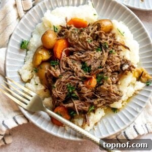 An overhead image of a beef chuck roast recipe with potatoes and carrots on a plate.