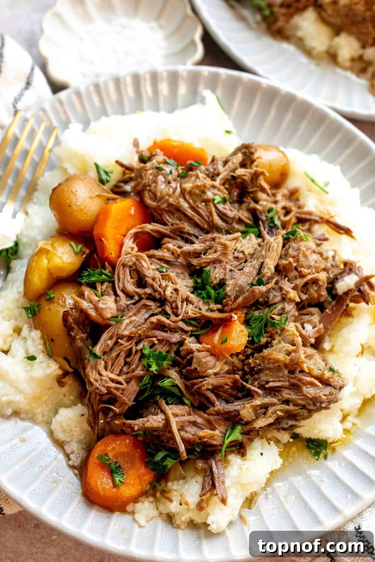 Fall-Apart Tender Chuck Roast 6 An overhead image of the finished beef chuck roast meal, with tender beef, vibrant carrots, and potatoes on a plate.