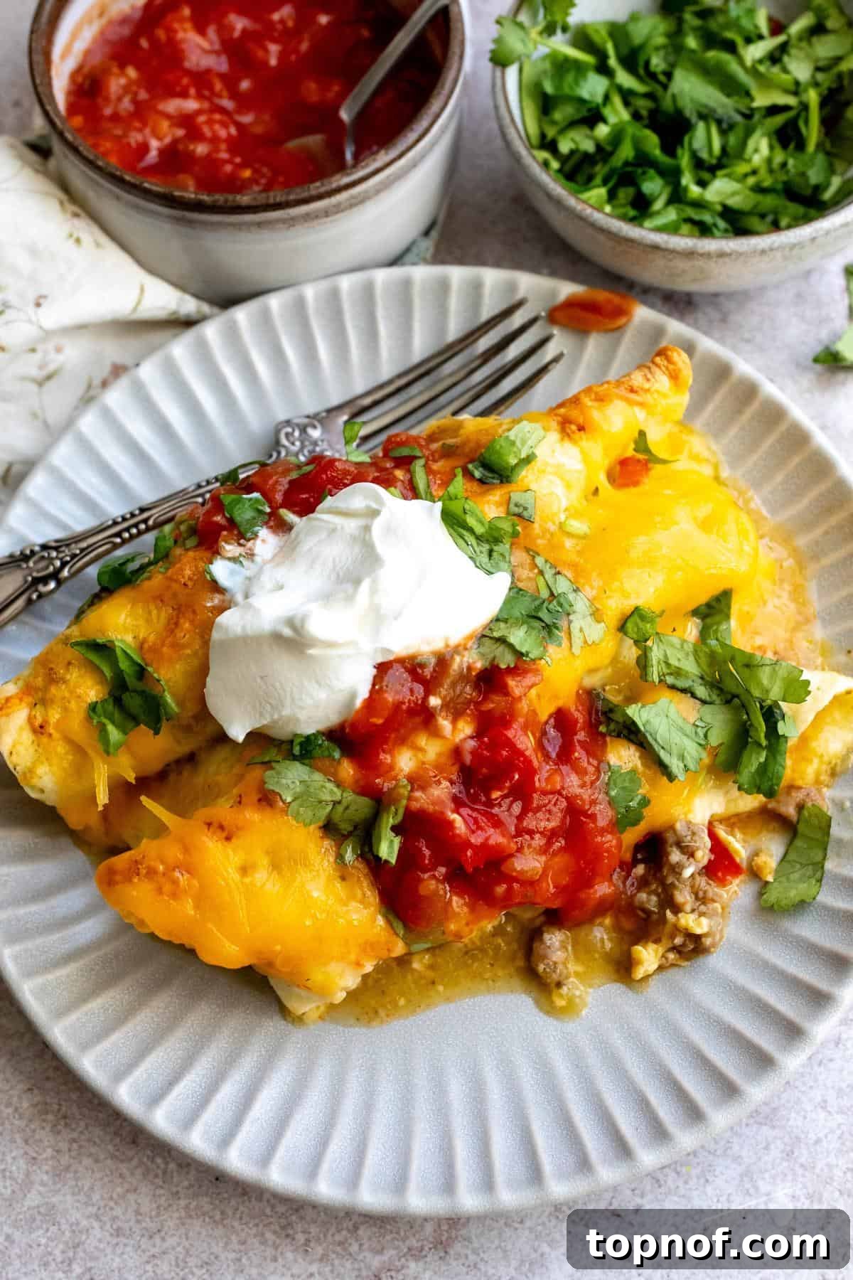 Breakfast Enchilada Casserole 2 Plate with Breakfast Enchiladas in it a fork on the side.