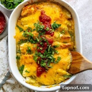 Breakfast Enchilada Casserole 7 White casserole dish with Breakfast Enchiladas in it and wooden spatula.