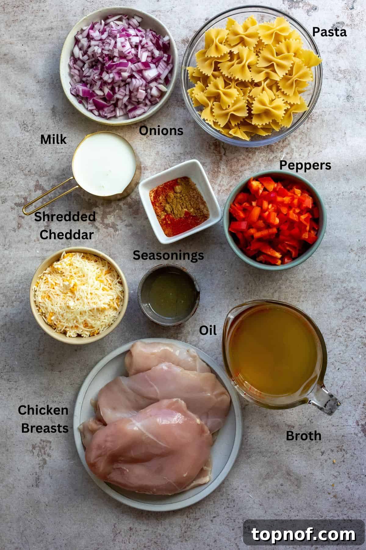 Tex-Mex Chicken Fajita Pasta 3 Bowls of fresh ingredients for Chicken Fajita Pasta, including chicken, bell peppers, onions, and spices, laid out on a grey counter.