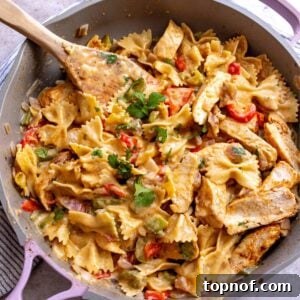 Close-up of creamy chicken fajita pasta in a pink and grey skillet, ready to serve.