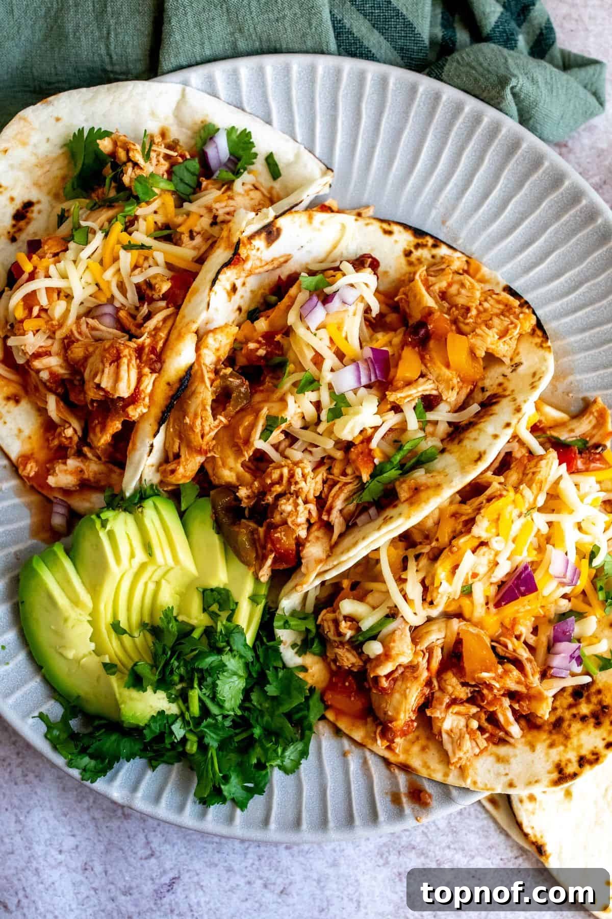 Weeknight Slow Cooker Chicken Tacos 2 Plate with lines on it and three slow cooker chicken tacos.