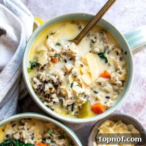 Velvety Chicken Wild Rice Soup 7 Soup bowls filled with Creamy Chicken Wild Rice Soup and a towel on the side, up close