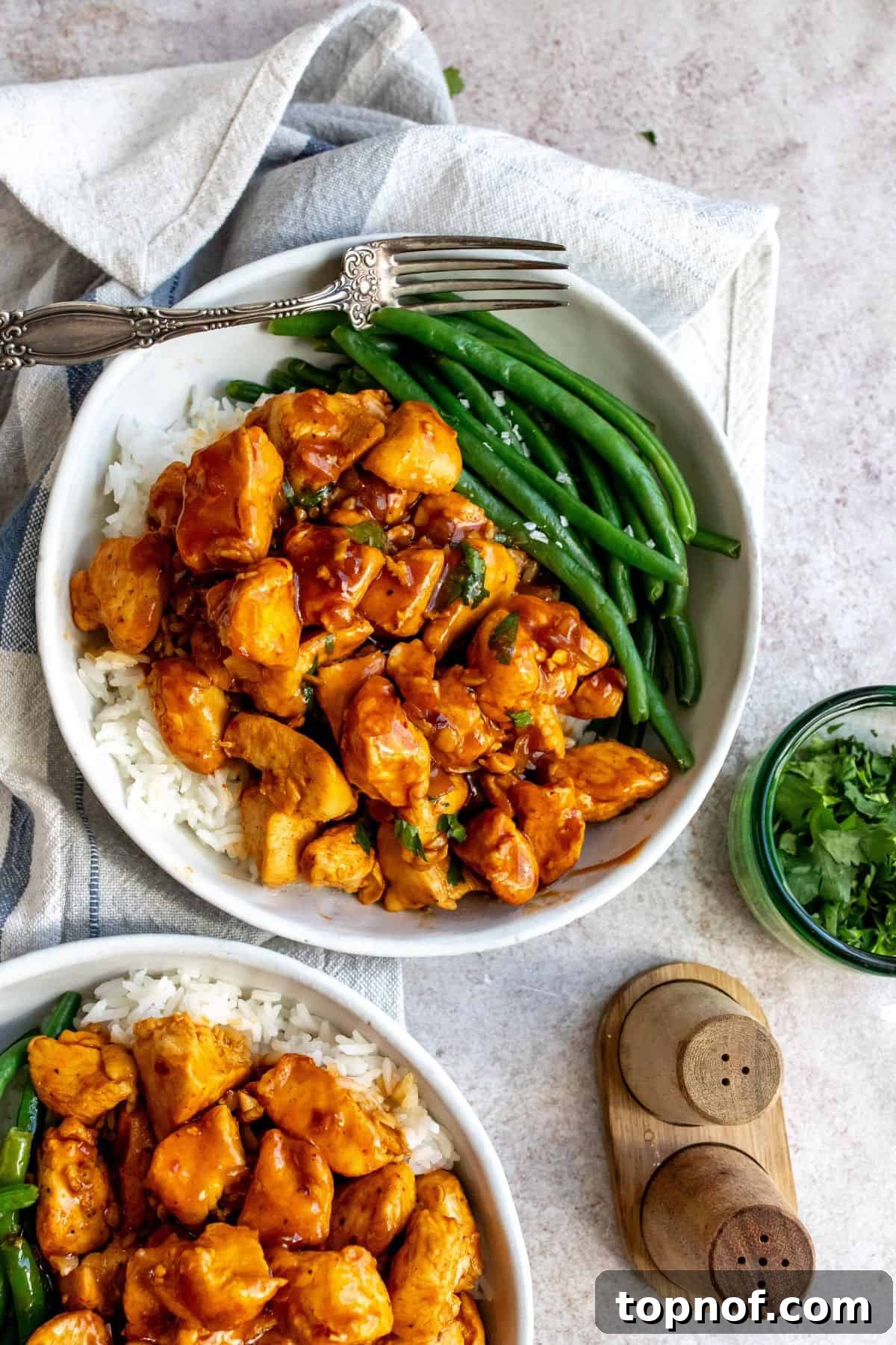 Golden Bourbon Honey Chicken 2 White bowl with Honey Bourbon Chicken and green beans, garnished with fresh cilantro.