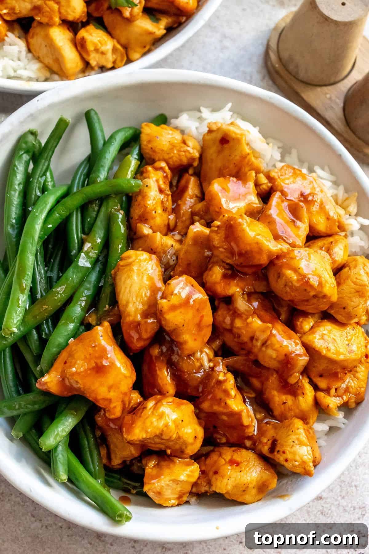 Golden Bourbon Honey Chicken 5 Close-up view of Honey Bourbon Chicken served in a white bowl with steamed green beans, ready to eat.