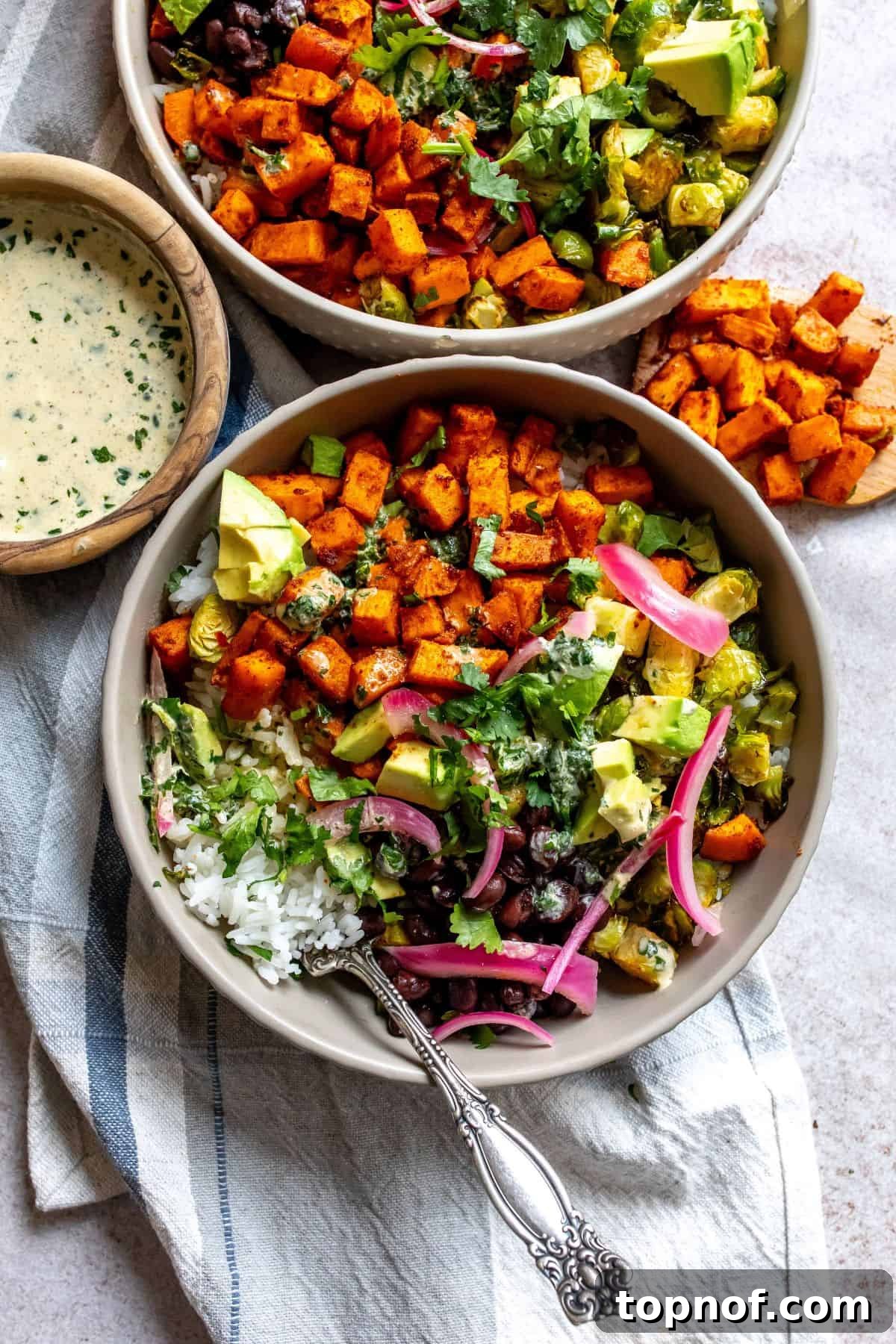 Wholesome Sweet Potato Bowls 2 Crispy, seasoned Sweet Potato Bowls drizzled with creamy cilantro lime dressing, ready to be enjoyed as a healthy vegetarian meal.