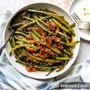 An overhead image of crack green beans on a plate, with golden-brown crispy bacon bits on top.