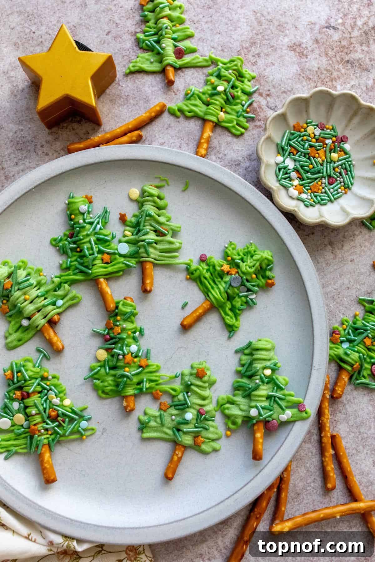Festive Pretzel Tree Treats 2 White plate with festive Pretzel Christmas Trees adorned with colorful sprinkles.