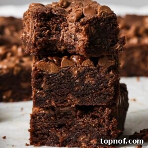 A stack of freshly baked Chocolate Chocolate Chip Cookie Bars on a pristine white counter, inviting to be tasted.