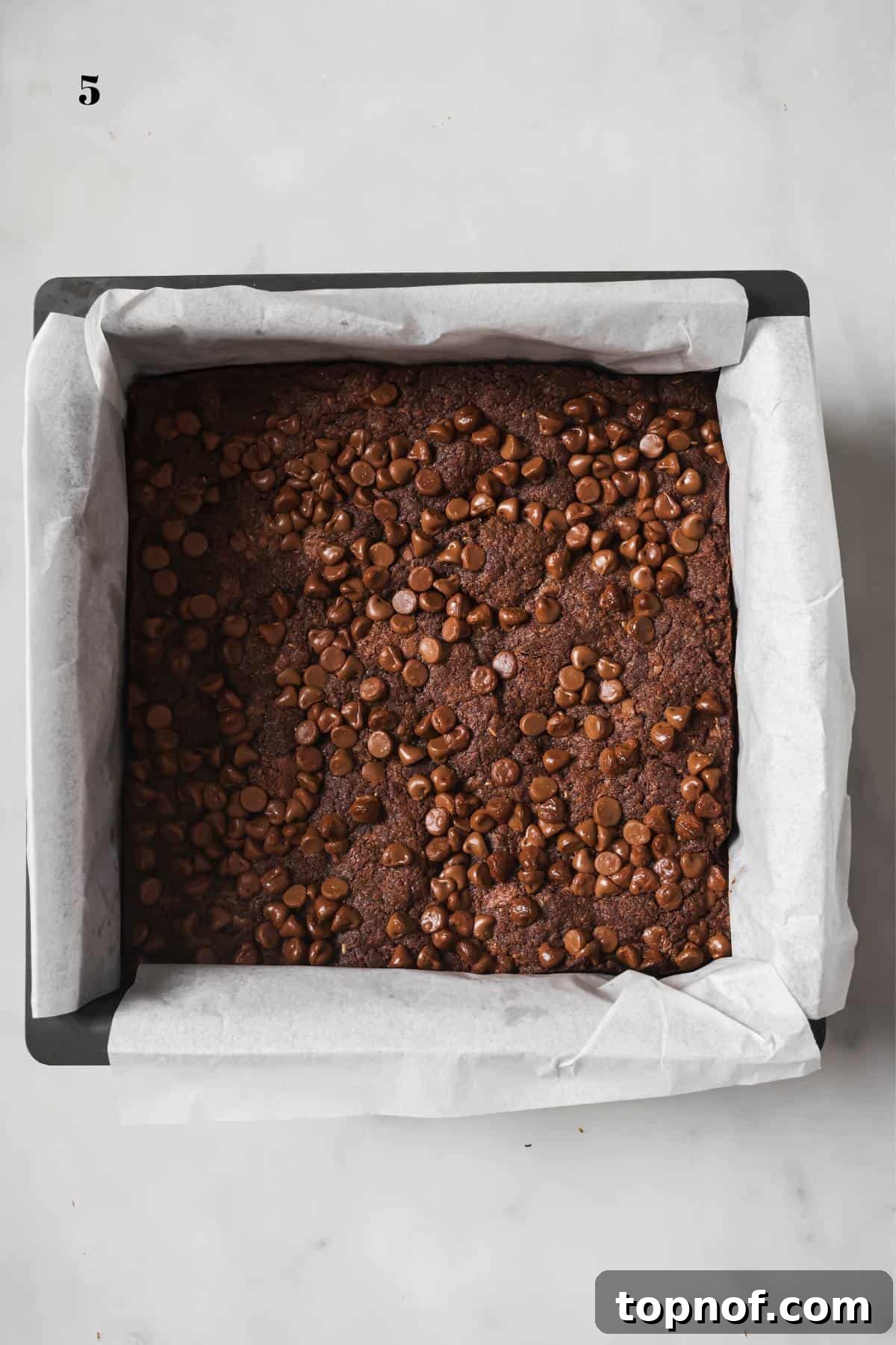 Double Chocolate Chip Cookie Bars 5 Perfectly baked Chocolate Chocolate Chip Cookie Bars cooling in the baking pan, still lined with white parchment paper, promising easy removal.