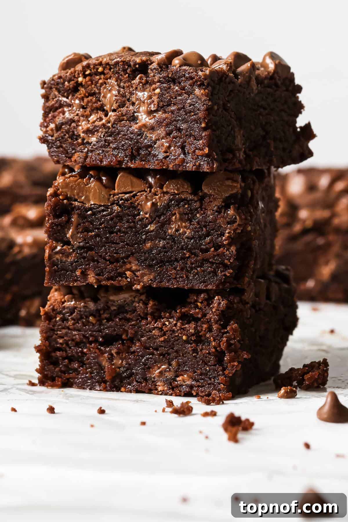 Double Chocolate Chip Cookie Bars 6 A delightful stack of warm, fudgy Chocolate Chocolate Chip Cookie Bars on a pristine white counter, ready to be enjoyed as a perfect treat.