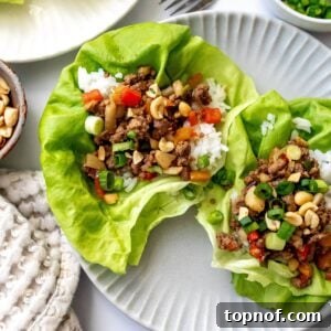 Ground Beef Lettuce Wraps on grey plates with a fork and onions on the side.
