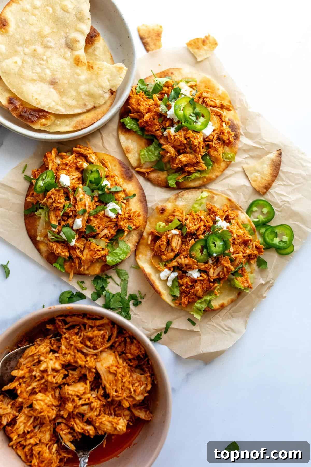 Smoky Chicken Tinga Tostadas 2 Crispy Chicken Tinga Tostadas on parchment paper with fresh jalapeños, ready to serve.