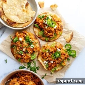 Chicken Tinga Tostadas on a white counter on parchment paper with jalapeños.