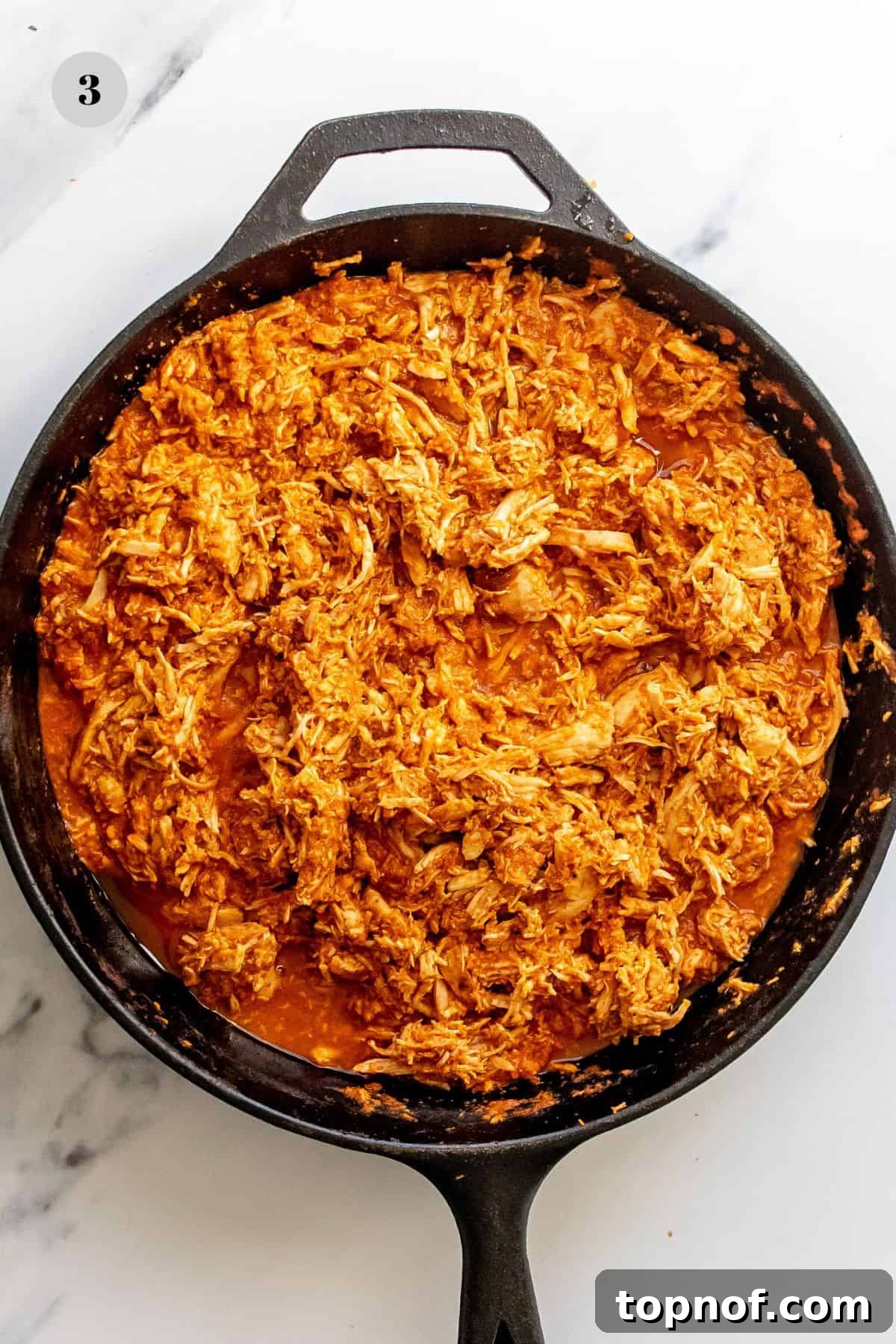 Smoky Chicken Tinga Tostadas 5 Shredded chicken generously coated in rich, smoky tinga sauce in a black cast iron skillet, ready for tostada assembly.