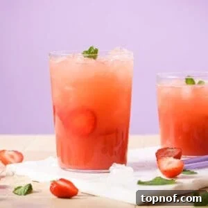 A glass of homemade strawberry acai refresher with ice and fresh strawberry slices.