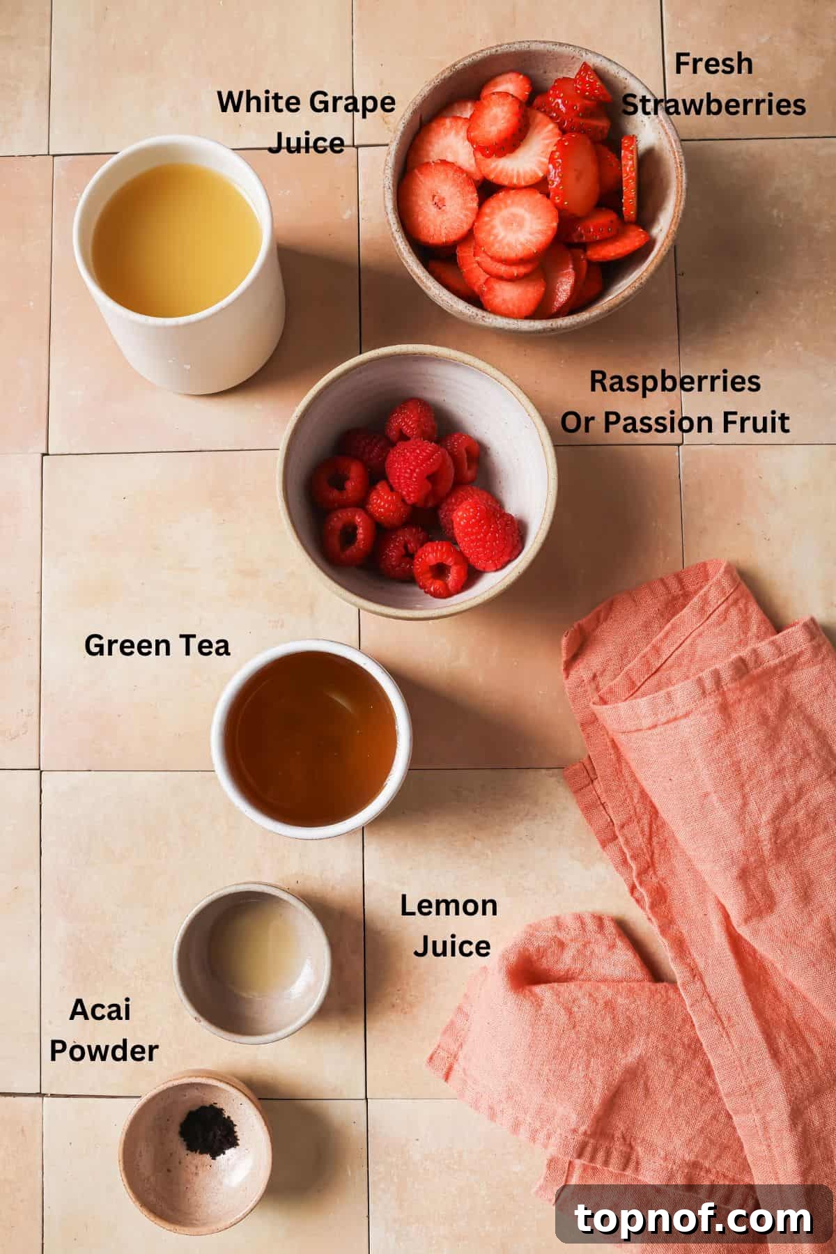 Homemade Strawberry Acai Burst 3 An overhead view of all the ingredients laid out for making the strawberry acai refresher, including strawberries, raspberries, green tea, grape juice, acai powder, and lemon.