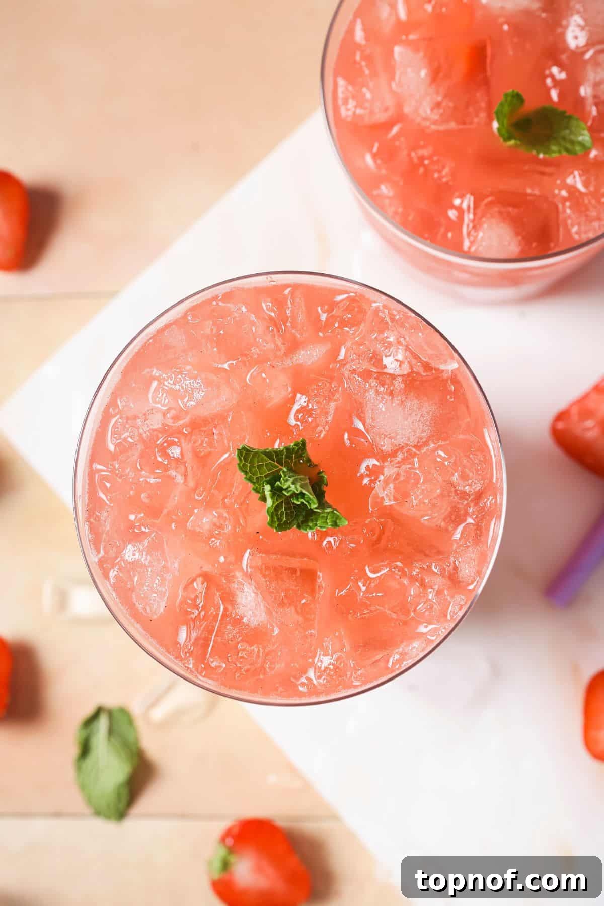 Homemade Strawberry Acai Burst 6 A close-up image of the top of a finished strawberry acai refresher, showing ice, strawberry slices, and a mint garnish.
