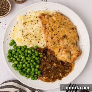 White ceramic plate with French onion soup chicken and peas and a fork to the side.