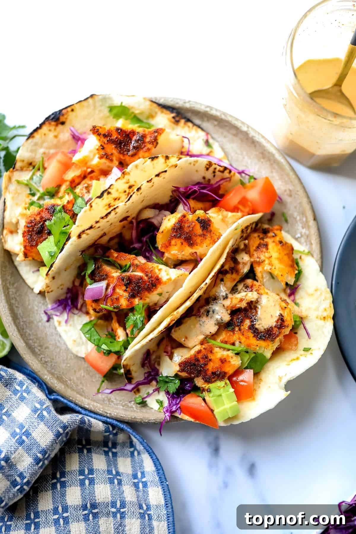 Cajun-Spiced Fish Tacos 2 Grey plate with beautifully arranged Blackened Fish Tacos, garnished with fresh cilantro and a vibrant blue towel to the side, highlighting the dish's appeal.